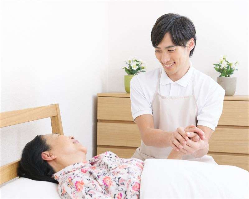 利用者の手を握っている男性介護士
